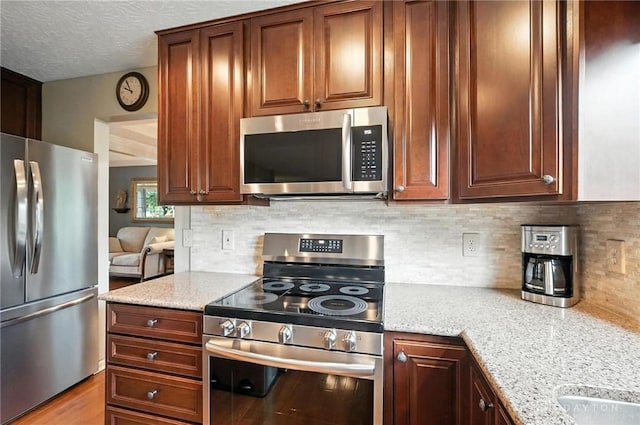 7793 Birchwood Ct, Mason, OH 45040 - kitchen featuring appliances with stainless steel finishes, tasteful backsplash, light stone countertops, and a textured ceiling