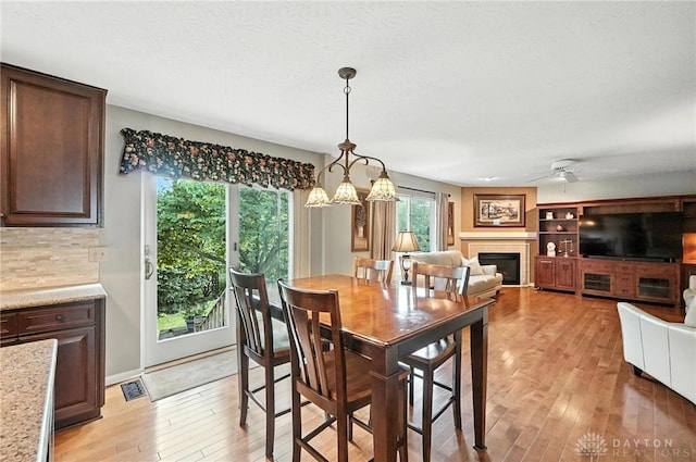 7793 Birchwood Ct, Mason, OH 45040 - dining room featuring light wood-style flooring, a ceiling fan, a tile fireplace, and a chandelier