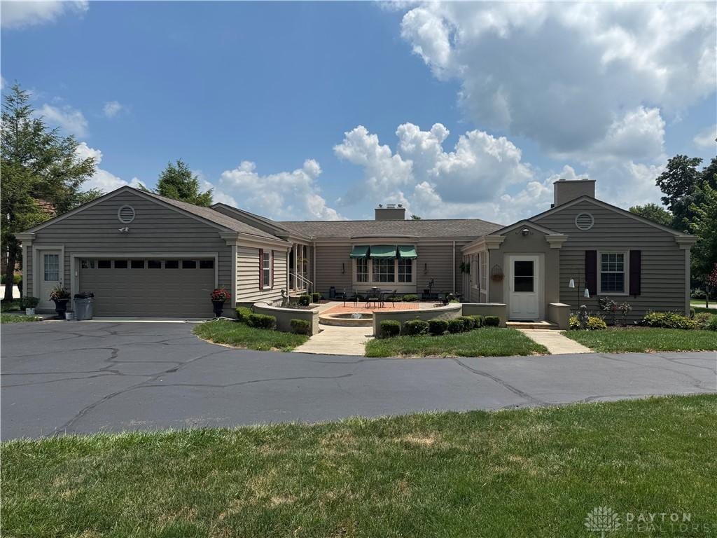 410 S Ridge Ave, Troy, OH 45373 - ranch-style house with asphalt driveway, a garage, a chimney, and a front yard