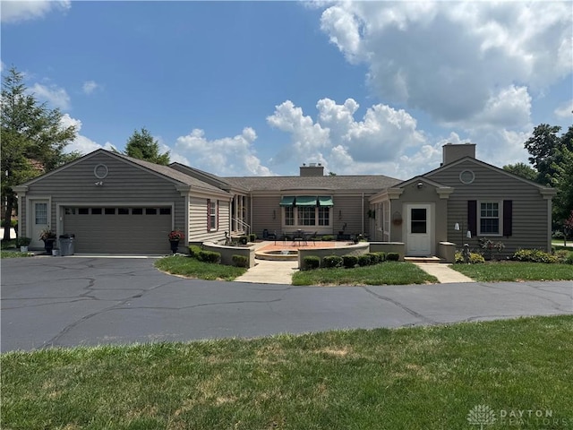 410 S Ridge Ave, Troy, OH 45373 - ranch-style house with asphalt driveway, a garage, a chimney, and a front yard