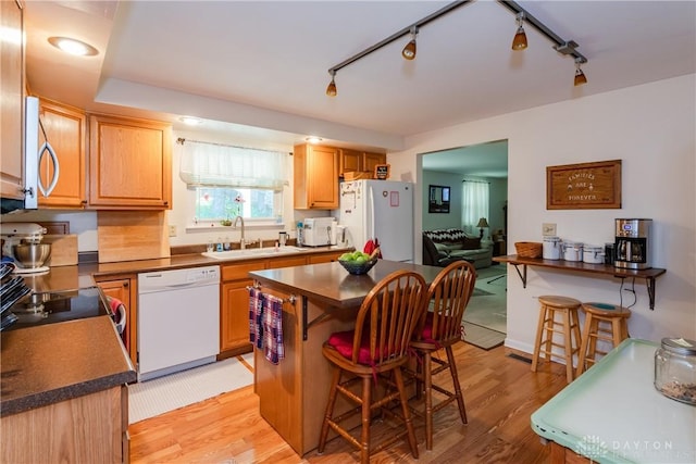 1269 Redbud Dr, Fairborn, OH 45324 - kitchen featuring white appliances, a breakfast bar area, dark countertops, light wood finished floors, and a kitchen island