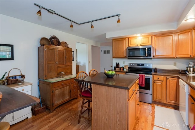 1269 Redbud Dr, Fairborn, OH 45324 - kitchen featuring appliances with stainless steel finishes, light wood-style floors, dark countertops, a breakfast bar area, and a center island