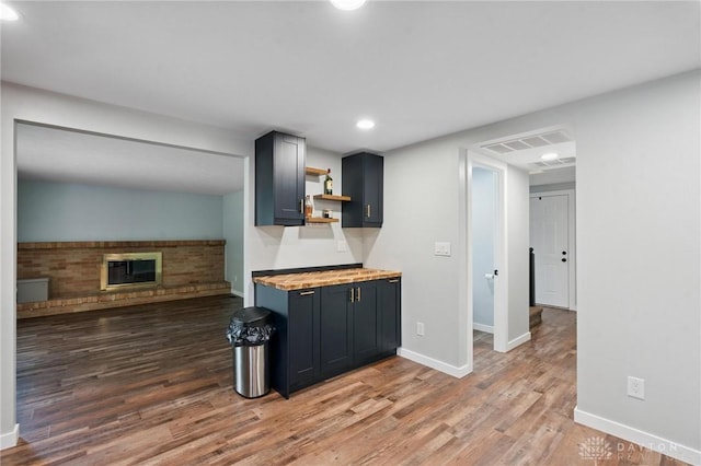 5433 Pentland Cir, Huber Heights, OH 45424 - kitchen featuring wooden counters, open shelves, wood finished floors, recessed lighting, and a brick fireplace