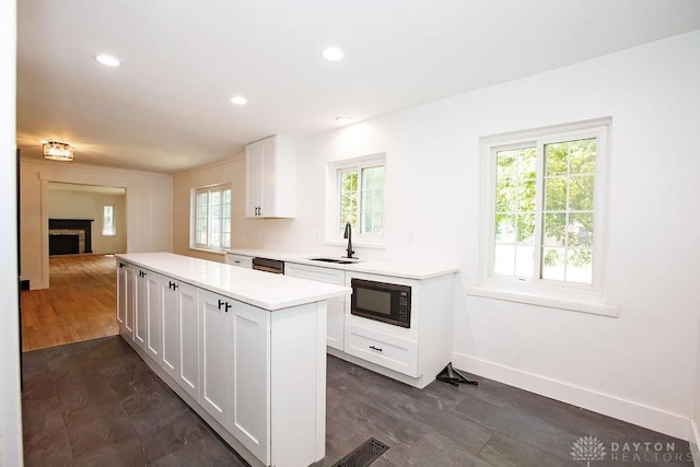 1151 Brookview Ave, Dayton, OH 45409 - kitchen featuring black microwave, a center island, light countertops, white cabinets, and a fireplace