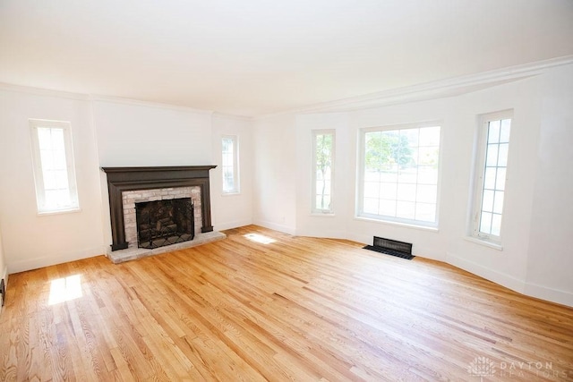 1151 Brookview Ave, Dayton, OH 45409 - unfurnished living room with a brick fireplace, plenty of natural light, light wood finished floors, and ornamental molding