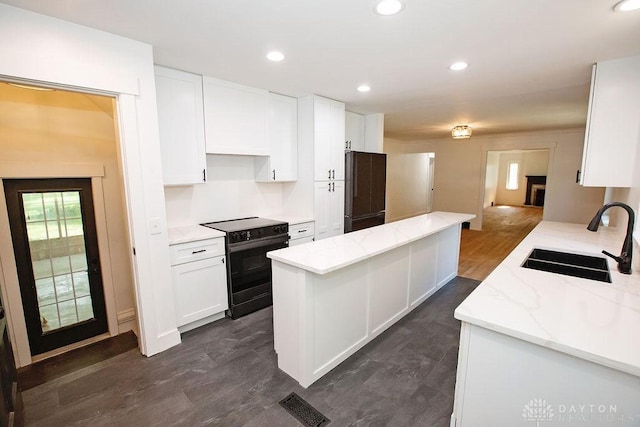 1151 Brookview Ave, Dayton, OH 45409 - kitchen featuring black electric range oven, stainless steel refrigerator, white cabinets, a kitchen island, and light stone counters