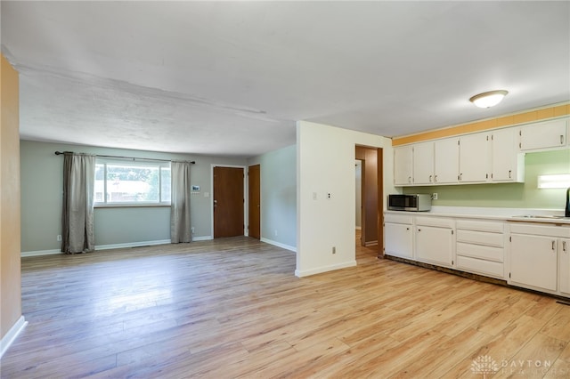 57 Pollyanna Ave, Germantown, OH 45327 - kitchen featuring stainless steel microwave, light wood finished floors, light countertops, white cabinetry, and open floor plan