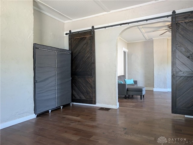 633 Taylor St, Dayton, OH 45404 - empty room with a barn door, a textured wall, dark wood-type flooring, crown molding, and arched walkways