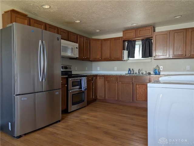 633 Taylor St, Dayton, OH 45404 - kitchen featuring stainless steel appliances, light wood-style floors, recessed lighting, a textured ceiling, and brown cabinetry