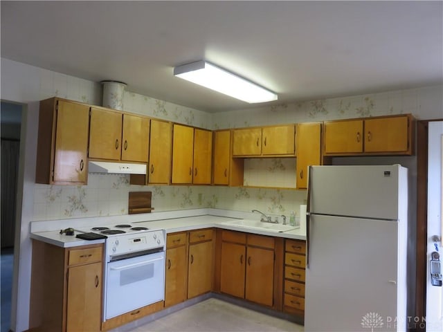 2830 Kennedy Ave, Dayton, OH 45420 - kitchen featuring white appliances, under cabinet range hood, light countertops, and brown cabinetry
