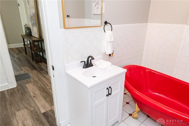 130 Mound St, Dayton, OH 45402 - bathroom with wood finished floors, a tub, vanity, a wainscoted wall, and tile walls