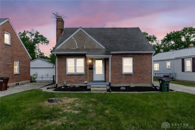 349 E Xenia Dr, Fairborn, OH 45324 - view of front of home with brick siding, a yard, a chimney, a shingled roof, and a detached garage
