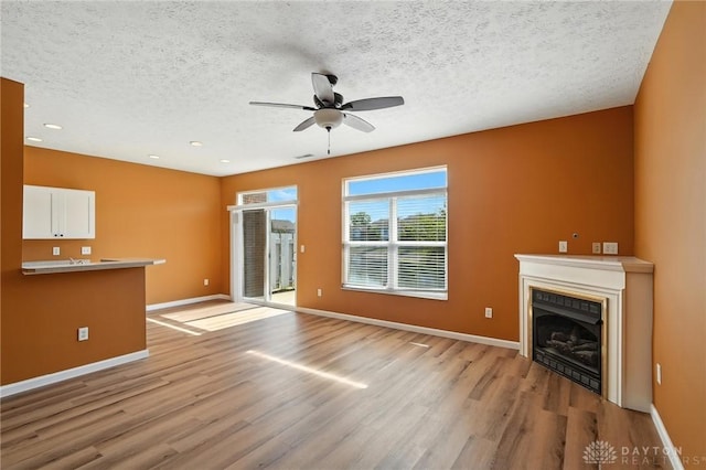 9266 Great Lakes Cir, Washington Twp, OH 45458 - unfurnished living room with light wood-style floors, ceiling fan, a textured ceiling, a fireplace, and recessed lighting