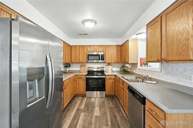 3755 Everett Dr, Loveland, OH 45140 - kitchen with appliances with stainless steel finishes, wood finished floors, light countertops, brown cabinetry, and backsplash