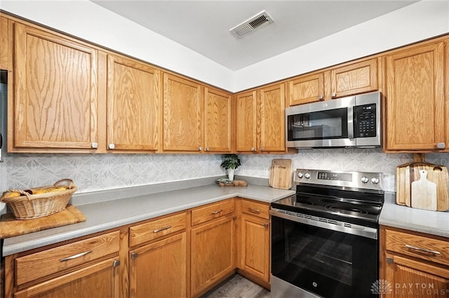 3755 Everett Dr, Loveland, OH 45140 - kitchen with appliances with stainless steel finishes, light countertops, tasteful backsplash, and brown cabinets