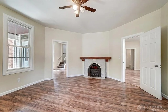233 Alton Ave, Dayton, OH 45404 - unfurnished living room featuring a ceiling fan, wood finished floors, a tiled fireplace, and stairs