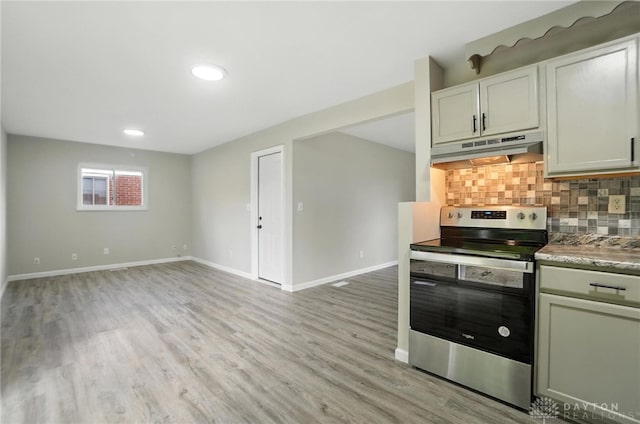 1393 Seminole Dr, Xenia, OH 45385 - kitchen featuring stainless steel electric range, under cabinet range hood, backsplash, light wood-style flooring, and open floor plan