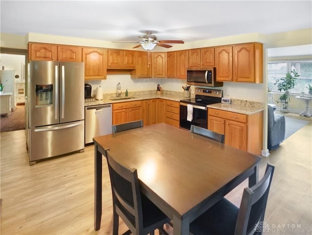 1464 New Way Dr, Beavercreek, OH 45434 - kitchen featuring stainless steel appliances, a ceiling fan, light stone countertops, light wood-style floors, and brown cabinetry