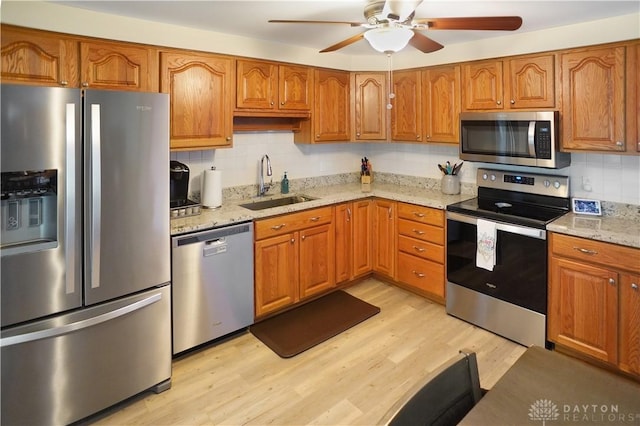 1464 New Way Dr, Beavercreek, OH 45434 - kitchen with stainless steel appliances, a ceiling fan, tasteful backsplash, brown cabinets, and light wood-style floors