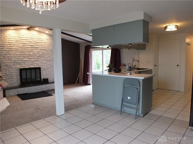 5582 Camerford Dr, Dayton, OH 45424 - kitchen featuring light carpet, light countertops, a peninsula, a breakfast bar area, and a stone fireplace