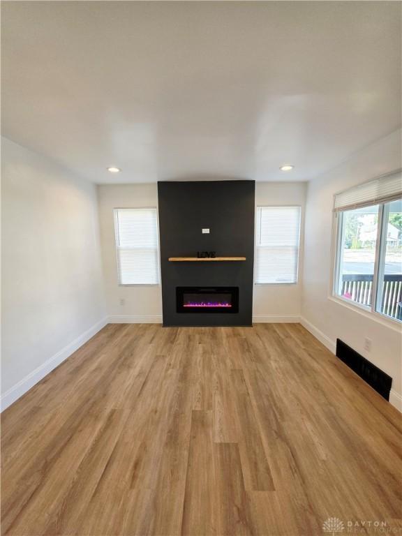 21 Anderson St, Dayton, OH 45410 - unfurnished living room featuring wood finished floors, a glass covered fireplace, plenty of natural light, and recessed lighting