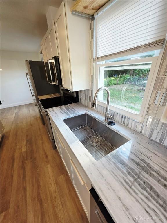 21 Anderson St, Dayton, OH 45410 - kitchen with tasteful backsplash, light stone countertops, white cabinetry, and wood finished floors