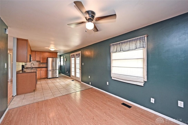 405 Parsons Ct, Englewood, OH 45322 - kitchen featuring freestanding refrigerator, a ceiling fan, brown cabinetry, dark countertops, and light wood-style flooring