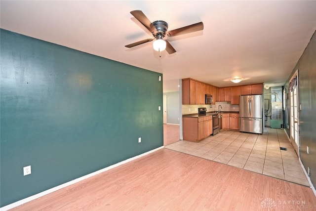 405 Parsons Ct, Englewood, OH 45322 - kitchen featuring stainless steel appliances, dark countertops, a ceiling fan, light wood-style flooring, and brown cabinetry