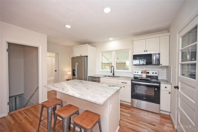 6383 Todhunter Rd, Middletown, OH 45044 - kitchen featuring stainless steel appliances, a kitchen bar, light wood finished floors, white cabinetry, and recessed lighting