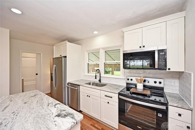 6383 Todhunter Rd, Middletown, OH 45044 - kitchen with appliances with stainless steel finishes, white cabinets, light wood-style flooring, light stone counters, and decorative backsplash