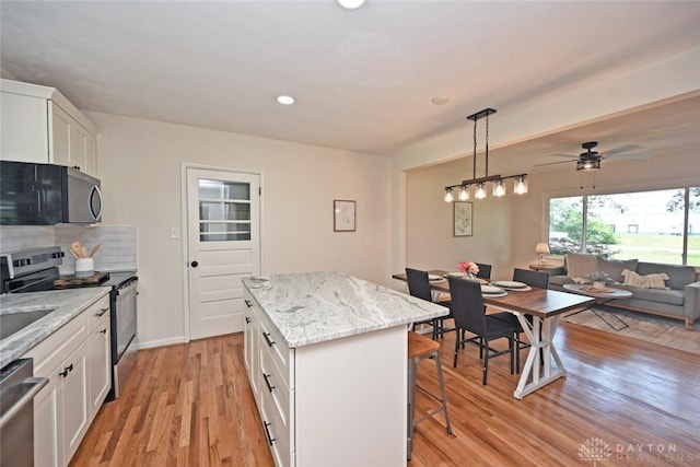 6383 Todhunter Rd, Middletown, OH 45044 - kitchen with appliances with stainless steel finishes, a kitchen bar, open floor plan, light wood-style flooring, and a center island