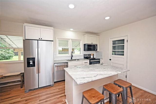 6383 Todhunter Rd, Middletown, OH 45044 - kitchen featuring appliances with stainless steel finishes, a breakfast bar area, white cabinetry, light wood-type flooring, and decorative backsplash