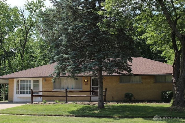 4912 Powell Rd, Huber Heights, OH 45424 - ranch-style house featuring brick siding, a front yard, a shingled roof, and a carport