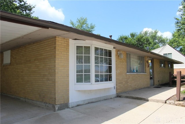 4912 Powell Rd, Huber Heights, OH 45424 - view of home's exterior featuring brick siding, a patio area, and an attached carport