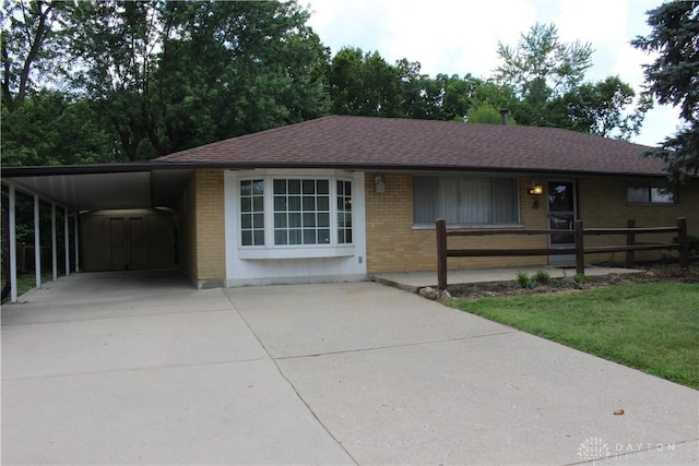 4912 Powell Rd, Huber Heights, OH 45424 - ranch-style house featuring driveway, brick siding, a carport, and roof with shingles