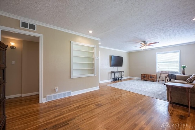 1097 Trudy Ct, Clearcreek Twp, OH 45036 - living area featuring a textured ceiling, crown molding, ceiling fan, wood finished floors, and built in shelves