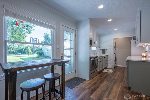 1097 Trudy Ct, Clearcreek Twp, OH 45036 - kitchen featuring stacked washer and clothes dryer, appliances with stainless steel finishes, dark wood finished floors, light countertops, and decorative backsplash