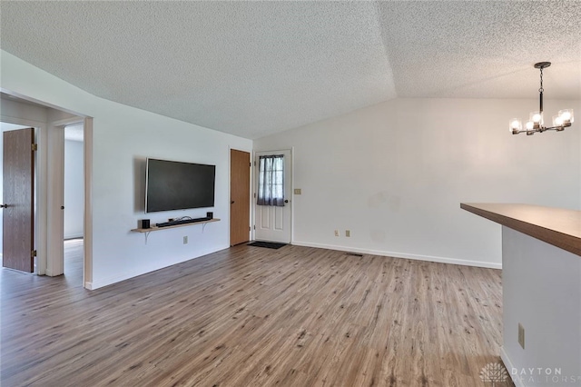 5979 Timbergate Trl, Dayton, OH 45424 - unfurnished living room with wood finished floors, a textured ceiling, a chandelier, and vaulted ceiling