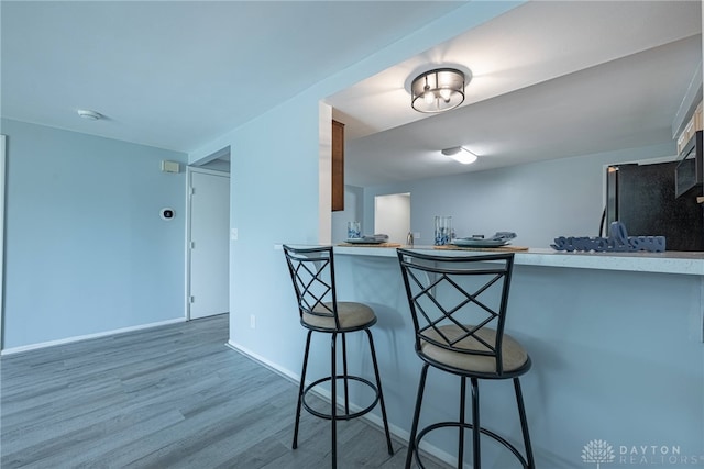 5970 Clearlake Dr, Dayton, OH 45424 - kitchen with wood finished floors, a kitchen bar, light countertops, and stainless steel appliances