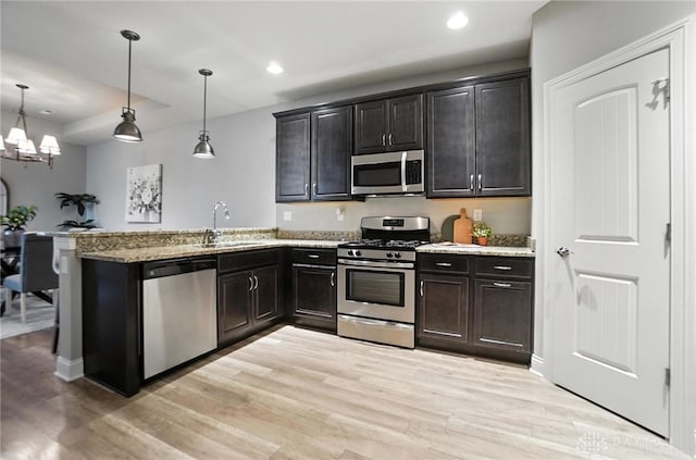 1310 Bourdeaux Way, Clearcreek Twp, OH 45458 - kitchen with stainless steel appliances, light wood-type flooring, light stone counters, recessed lighting, and a chandelier