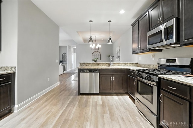 1310 Bourdeaux Way, Clearcreek Twp, OH 45458 - kitchen with stainless steel appliances, a peninsula, light wood finished floors, a chandelier, and decorative light fixtures
