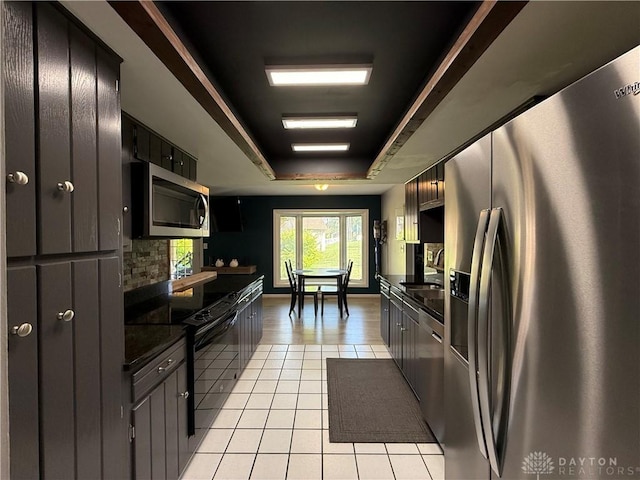 4220 Sillman Pl, Kettering, OH 45440 - kitchen featuring stainless steel appliances, light tile patterned floors, dark countertops, and a raised ceiling