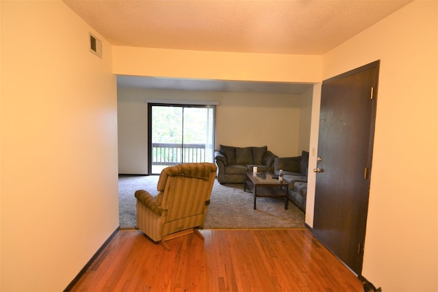 living room featuring visible vents, a textured ceiling, and wood finished floors