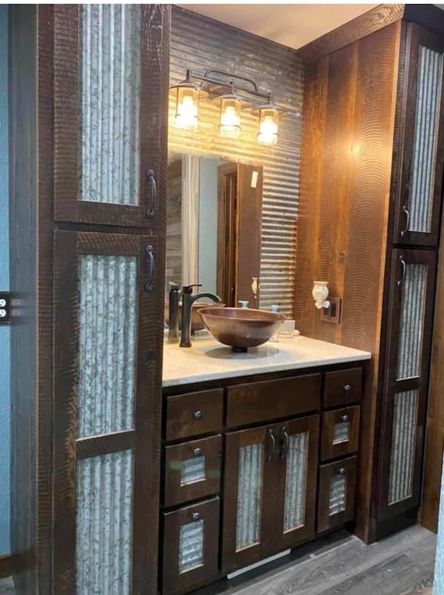 bathroom with wooden walls, hardwood / wood-style floors, and vanity