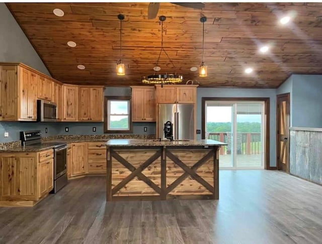 kitchen featuring pendant lighting, dark hardwood / wood-style floors, dark stone countertops, and stainless steel appliances