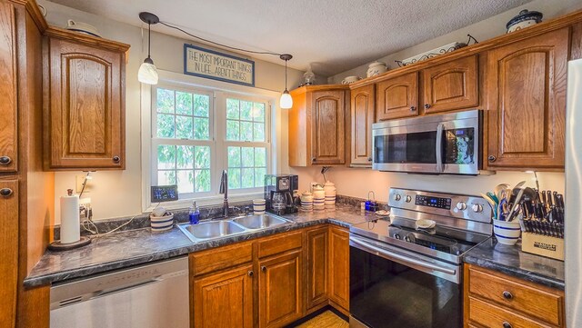 26484 State Highway 3, Kirksville, MO 63501 - kitchen featuring stainless steel appliances, dark countertops, brown cabinetry, hanging light fixtures, and a textured ceiling