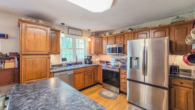 26484 State Highway 3, Kirksville, MO 63501 - kitchen with appliances with stainless steel finishes, dark countertops, brown cabinets, light wood finished floors, and a textured ceiling