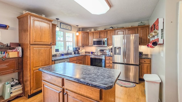26484 State Highway 3, Kirksville, MO 63501 - kitchen featuring appliances with stainless steel finishes, dark countertops, light wood-style floors, brown cabinetry, and a center island