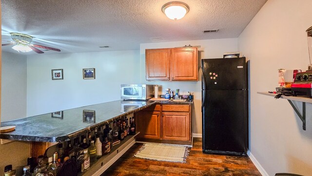 26484 State Highway 3, Kirksville, MO 63501 - kitchen featuring freestanding refrigerator, stainless steel microwave, dark wood-style flooring, dark countertops, and a textured ceiling