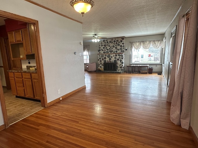 unfurnished living room with dark hardwood / wood-style floors, a stone fireplace, a wealth of natural light, and ceiling fan